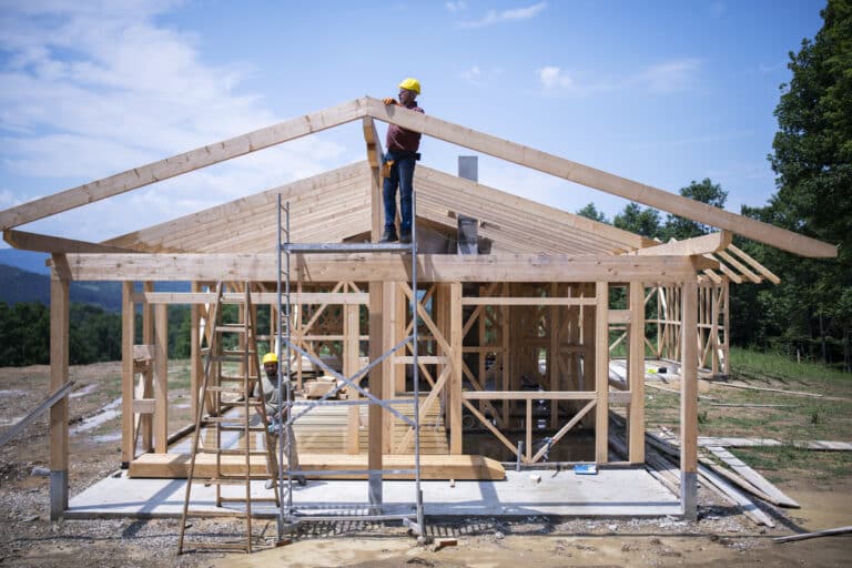 Two construction workers working on a house
