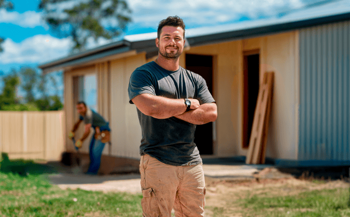 Smiling builder standing in front of a small home build