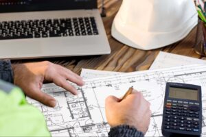 A builder works with construction plans on desk